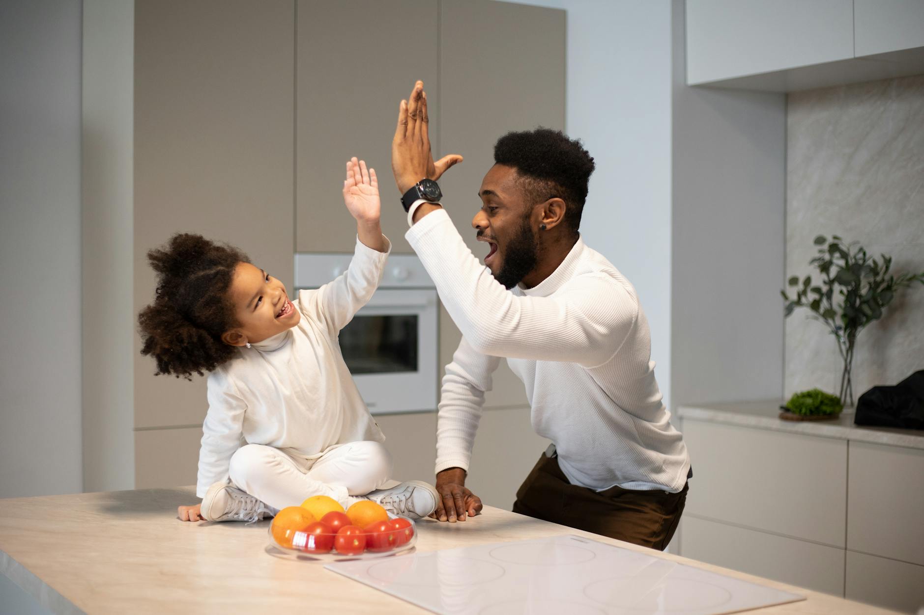 joyful black father giving high five to adorable daughter